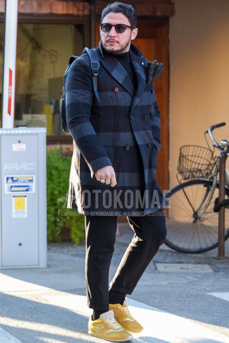 Men's fall/winter outfit with plain black sunglasses from Boston, gray/black checked chester coat, plain black turtleneck knit, dark gray plain slacks, plain black socks, and yellow low-cut sneakers.