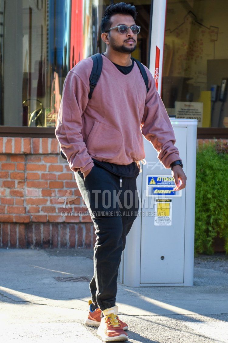 Men's spring/fall outfit with clear solid color sunglasses from Boston, solid color pink sweatshirt, solid color black t-shirt, dark gray solid color jogger pants/ribbed pants, dark gray solid color sweatpants, brown low-cut sneakers.