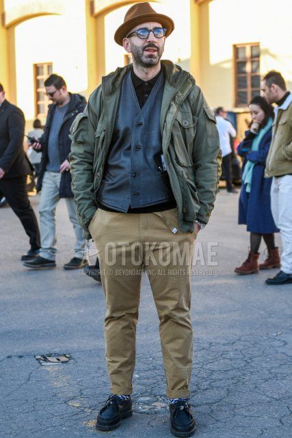 Men's fall/winter outfit with plain brown hat, plain black Boston sunglasses, plain olive green field jacket/hunting jacket, plain gray gilet, plain black polo shirt, plain beige chinos, black/white checked socks, black Tyrolean leather shoes. Outfit.