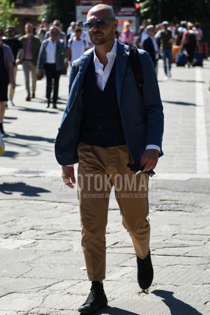 Spring and fall men's coordinate and outfit with clear blue solid sunglasses, Lardini blue solid tailored jacket, black solid gilet, white solid shirt, beige solid chinos, solid pleated pants, and black high-cut sneakers.