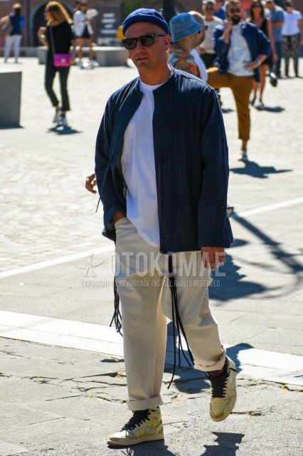Men's spring, summer, and fall coordinate and outfit with plain navy knit cap, plain black Wellington sunglasses, plain dark gray outerwear, plain white t-shirt, plain beige chinos, and beige high-cut Nike sneakers.