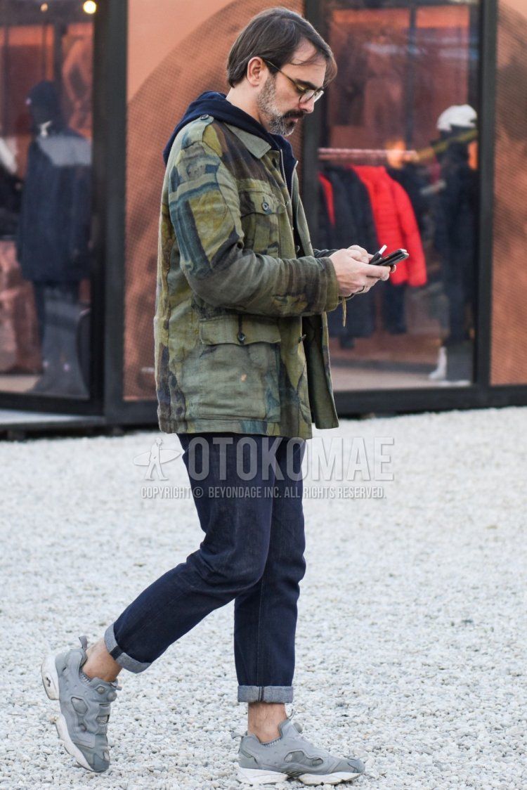 Men's fall/winter coordinate and outfit with brown tortoiseshell glasses, olive green outer shirt jacket, navy solid color hoodie, navy solid color denim/jeans, and Reebok Instapump Fury gray low-cut sneakers.