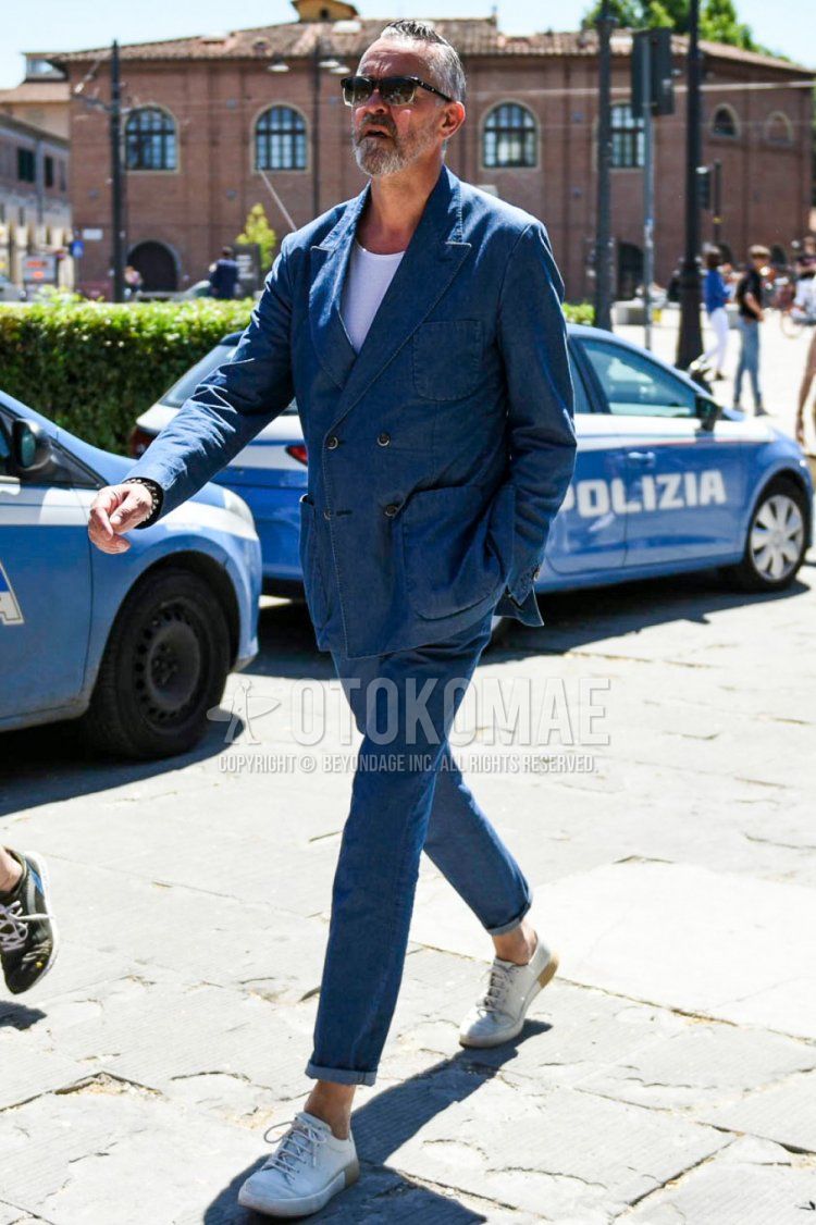 Men's spring/summer coordinate and outfit with olive green/clear solid sunglasses, solid white t-shirt, white low-cut sneakers, and solid blue suit.