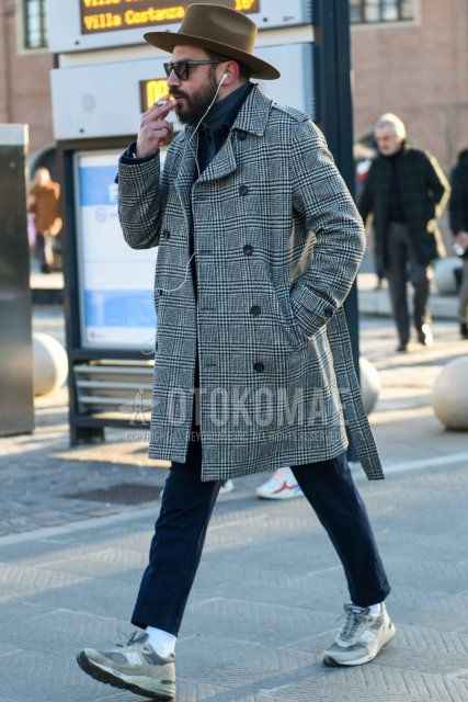 A solid beige hat, solid black sunglasses, a gray checked trench coat, a solid black trucker jacket, a solid gray turtleneck knit, dark gray solid slacks, dark gray solid ankle pants, solid white socks, and a pair of New Balance low-cut gray sneakers. Sneakers, and a pair of New Balance low-cut gray sneakers.