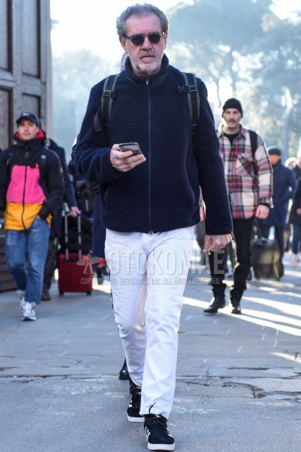 Men's fall/winter coordinate and outfit with dark gray tortoiseshell sunglasses, solid black fleece jacket, solid white cotton pants, solid white ankle pants, and Adidas Campus black low-cut sneakers.
