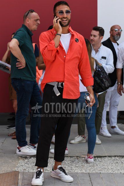 Men's spring/summer coordinate and outfit with clear solid sunglasses, solid orange shirt, solid white t-shirt, white/black striped tape belt, solid black sarouel pants, and white low-cut sneakers by Diadora.