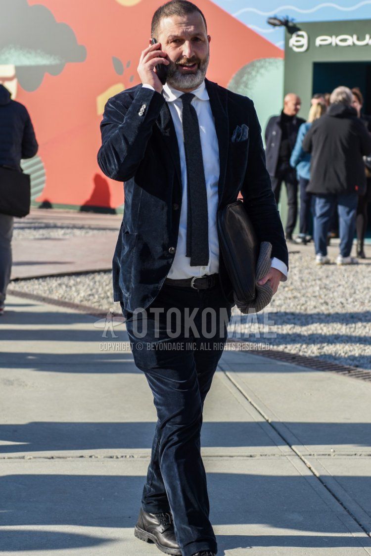 Men's spring/autumn coordination and outfit with plain white shirt, plain black leather belt, plain black clutch bag/second bag/drawstring, plain navy suit, and plain gray tie.