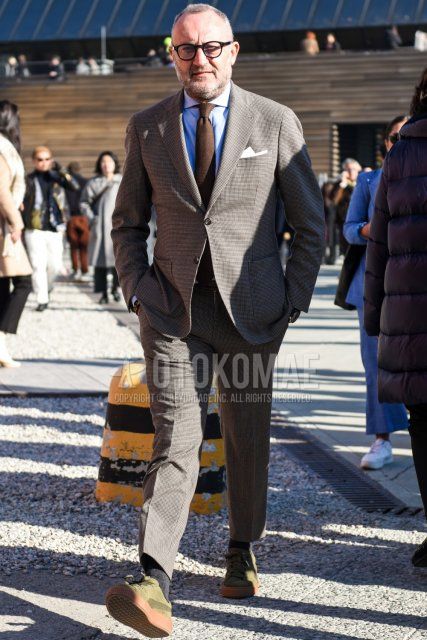Men's spring and fall outfit and outfit with plain black glasses, plain white shirt, plain black socks, olive green low-cut sneakers with Puma suede, gray checked suit, and plain brown tie.