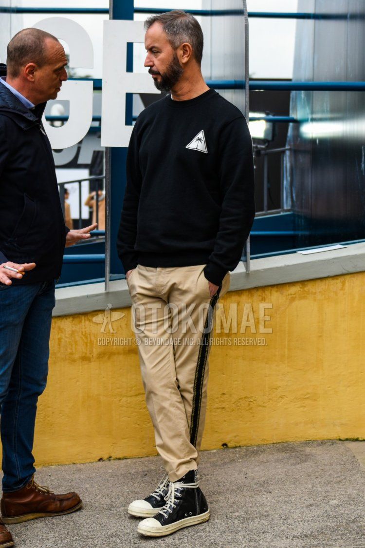 Men's spring and fall coordinate and outfit with black one-piece trainers, solid beige sideline pants, solid beige chinos, and black high-cut sneakers.