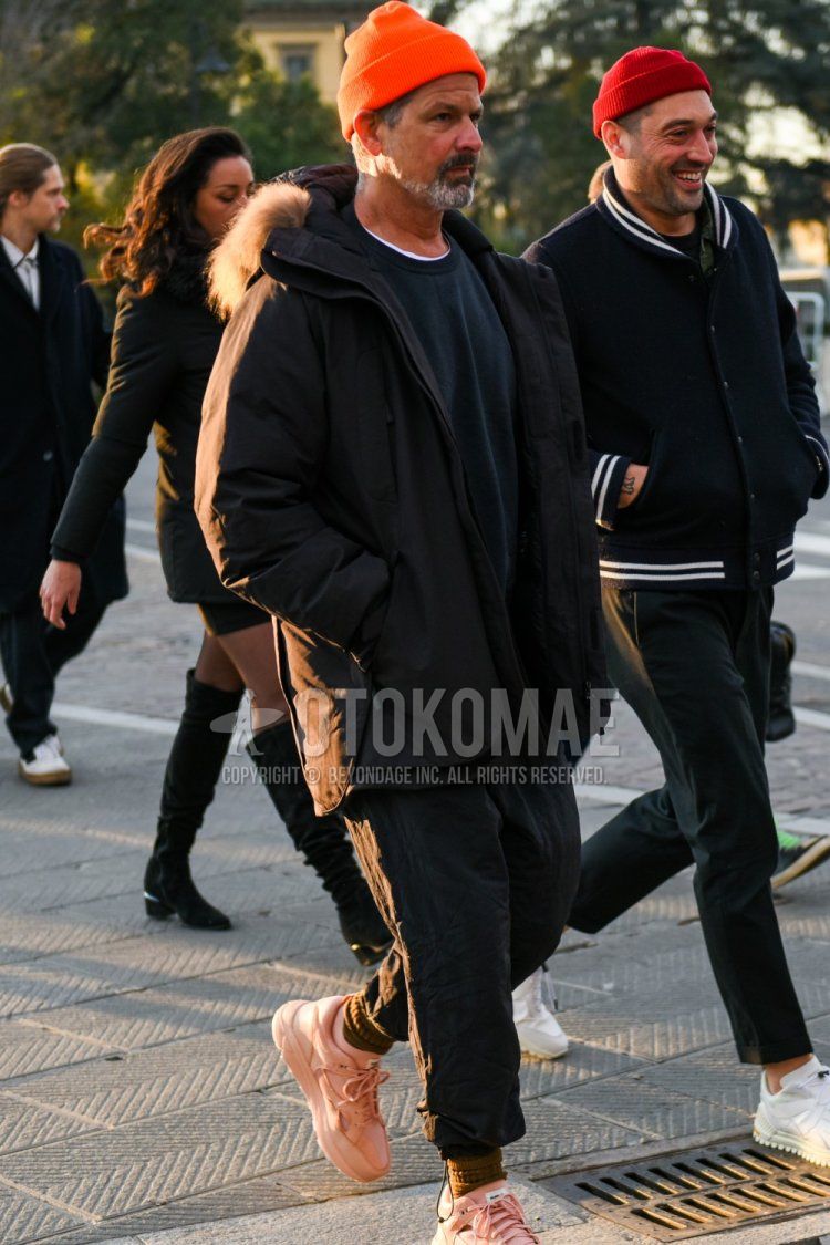 Men's winter coordinate and outfit with solid orange knit cap, solid black hooded coat, solid black down jacket, solid black sweatshirt, solid black jogger pants/ribbed pants, solid beige socks, and pink low-cut sneakers.