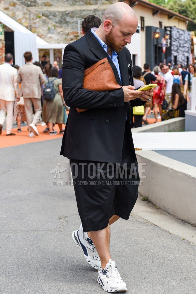 Men's spring/summer/autumn coordinate and outfit with plain black tailored jacket, plain light blue shirt, plain black shorts, white low-cut sneakers, and plain brown clutch/second bag/drawstring bag.