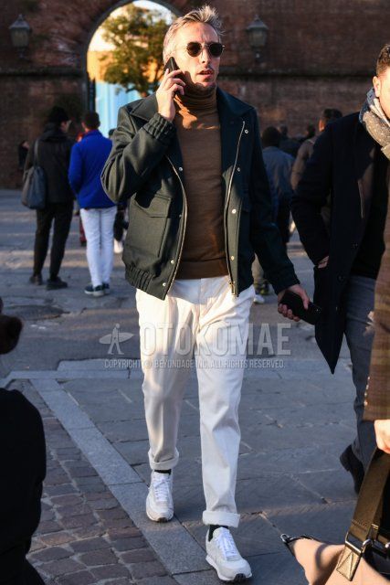 Men's fall/winter outfit with brown tortoiseshell sunglasses, solid black outerwear, solid beige turtleneck knit, solid white slacks, solid black socks, and Nike white/gray low-cut sneakers.
