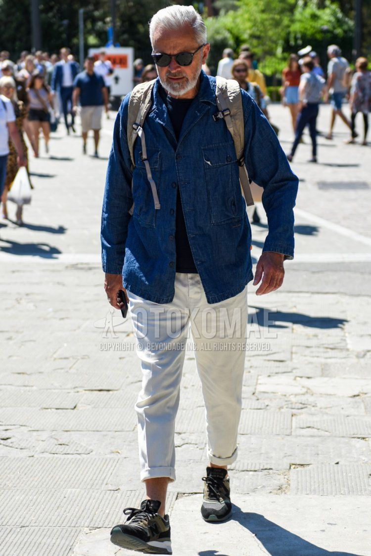 Men's spring and fall outfit with Boston plain black sunglasses, plain blue denim jacket, plain navy t-shirt, plain white cotton pants, and New Balance olive green low-cut sneakers.