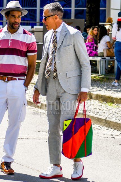 Men's spring, summer, and fall coordination and outfit with plain sunglasses, plain white shirt, white low-cut sneakers, multi-colored bag tote bag, gray suit suit, and beige necktie tie.