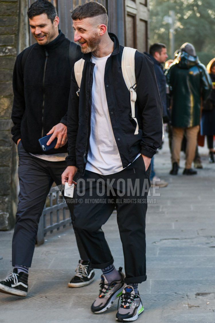 Men's spring and summer coordinate and outfit with plain black shirt jacket, plain black t-shirt, plain gray socks, gray low-cut sneakers, and plain white backpack.