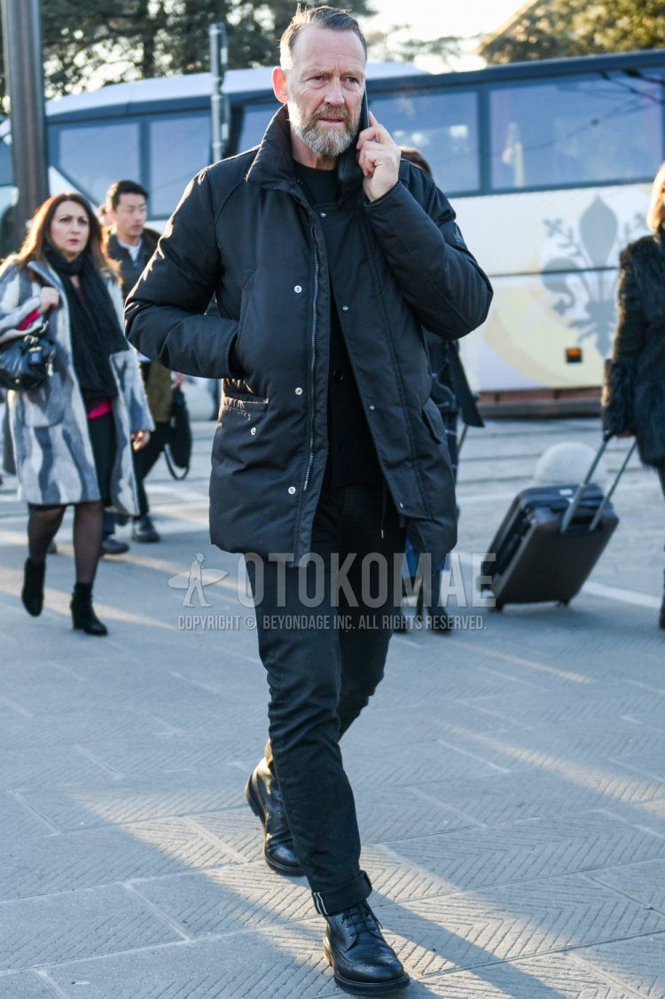 Men's fall/winter coordinate and outfit with plain black down jacket, plain black sweatshirt, dark gray plain denim/jeans, and black boots.