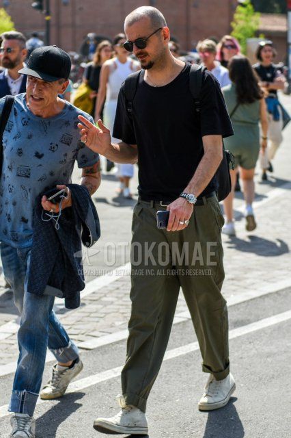 Men's summer coordinate and outfit with plain black sunglasses, plain black t-shirt, olive green plain wide-leg pants, and white high-cut Converse sneakers.
