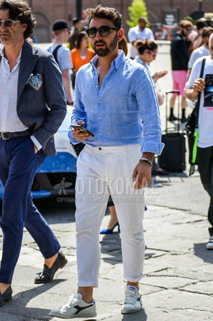 Men's spring and summer coordinate and outfit with plain black sunglasses, linen light blue plain shirt, plain white beltless pants, and white low-cut sneakers by Diadora.