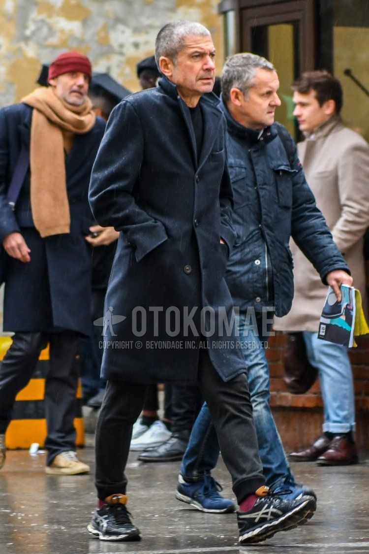Winter men's coordinate and outfit with dark gray solid color chester coat, black solid color sweater, dark gray solid color jogger pants/ribbed pants, red solid color socks, and black low-cut sneakers by Asics.