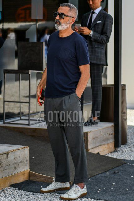 Men's summer coordinate and outfit with plain black sunglasses, plain navy t-shirt, plain gray slacks, and white low-cut sneakers by Diadora.