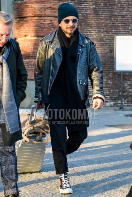 Men's fall/winter coordinate and outfit with solid black knit cap, solid clear sunglasses, solid black scarf/stall, solid black rider's jacket, solid black cropped pants, and Play Comme des Garçons Converse Chuck Taylor black high-cut sneakers.