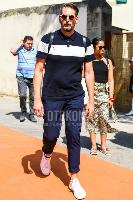 Men's summer coordinate and outfit with solid beige sunglasses, solid black polo shirt, solid gray slacks, and white low-cut Reebok sneakers.