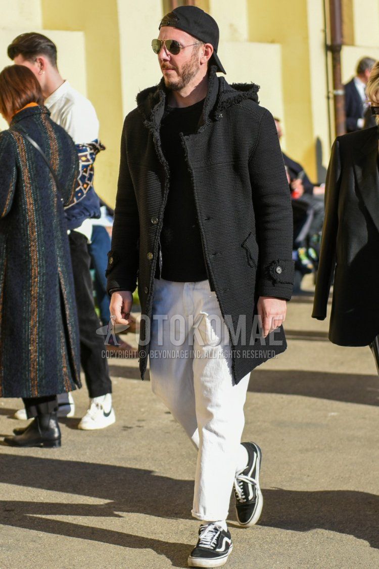 Men's fall/winter coordinate and outfit with solid black baseball cap, solid gold sunglasses with teardrops, solid black hooded coat, solid black sweater, solid white cotton pants, solid white socks, and Vans Old Skool black low-cut sneakers.