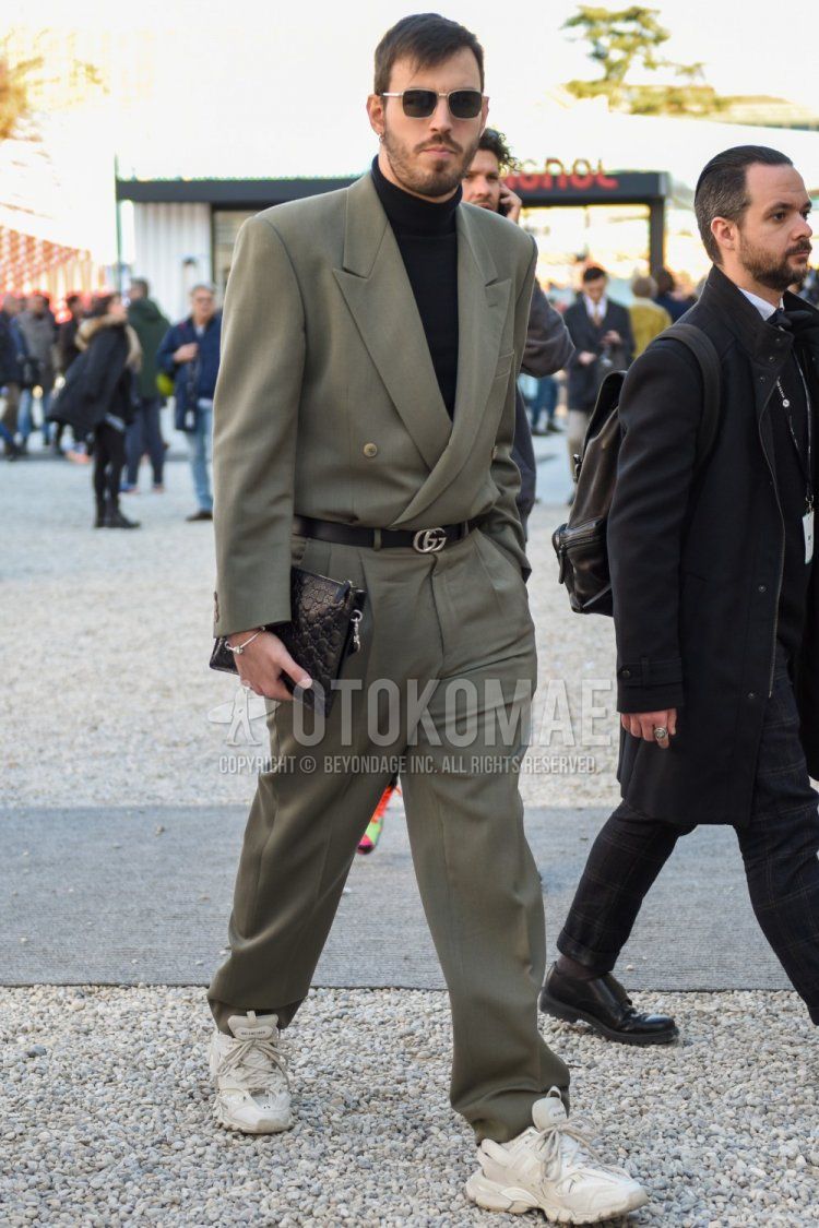Spring and fall men's outfit with plain silver sunglasses, plain gray jumpsuit, plain black turtleneck knit, plain black leather belt by Gucci, white low-cut sneakers with Balenciaga track trainers, plain black clutch bag/second bag/drawstring by Gucci Outfit.
