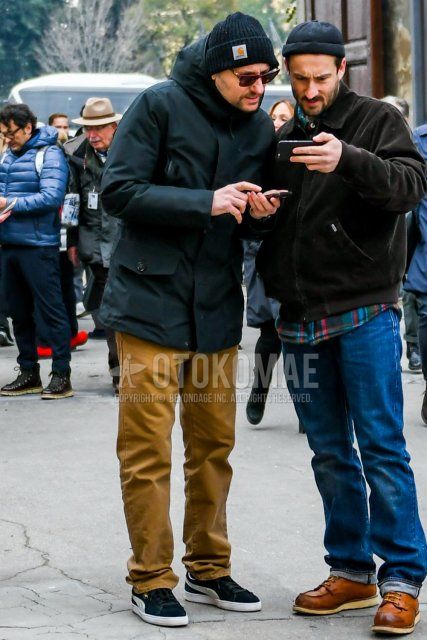 Winter men's coordinate and outfit with plain black knit cap, plain black mountain parka, plain brown chinos, and black low-cut Puma sneakers.