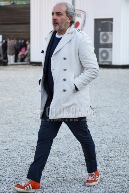 Men's fall/winter coordinate and outfit with plain white trench coat, plain navy sweater, plain white t-shirt, plain navy slacks, plain navy ankle pants, and Adidas orange high-cut sneakers.