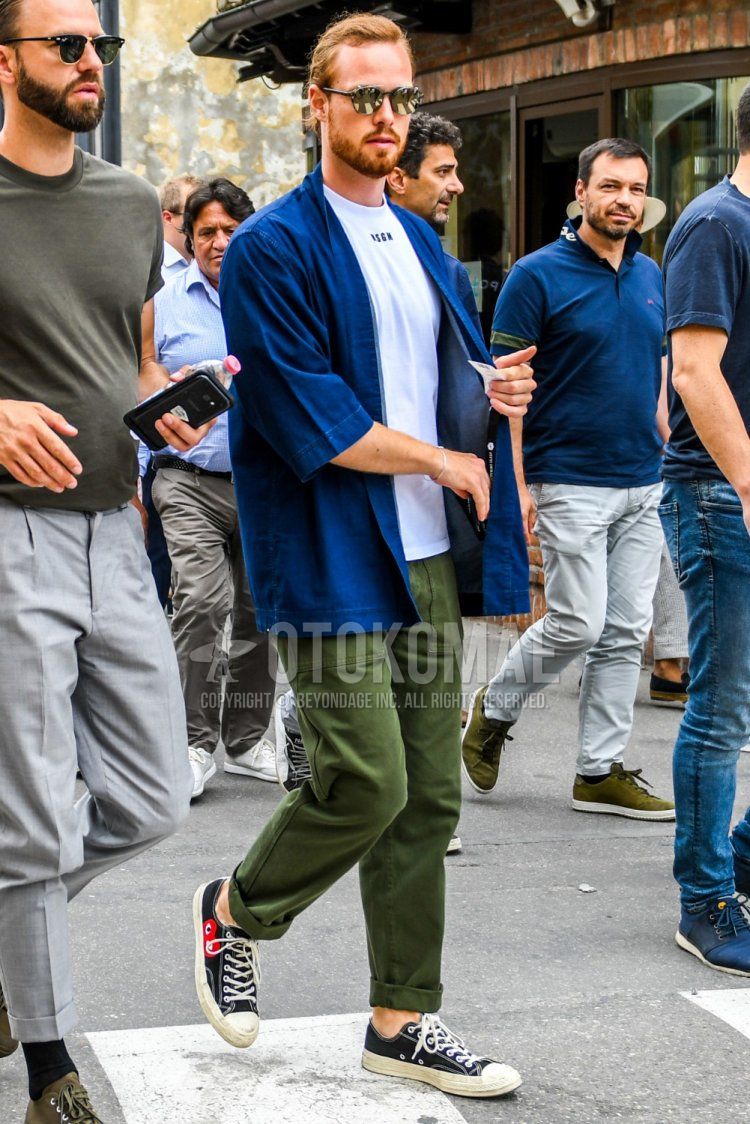 Men's spring/summer coordinate and outfit with solid color sunglasses, solid color blue outerwear, solid color white t-shirt, solid color olive green chinos and Comme des Garcons Play Converse Chuck Taylor black low-cut sneakers.