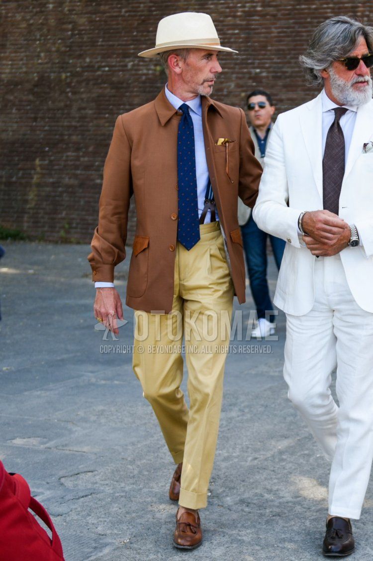 Men's spring and fall outfit with solid beige hat, solid brown shirt jacket, solid light blue shirt, solid brown suspenders, solid beige chinos, solid pleated pants, brown tassel loafer leather shoes, and navy tie.