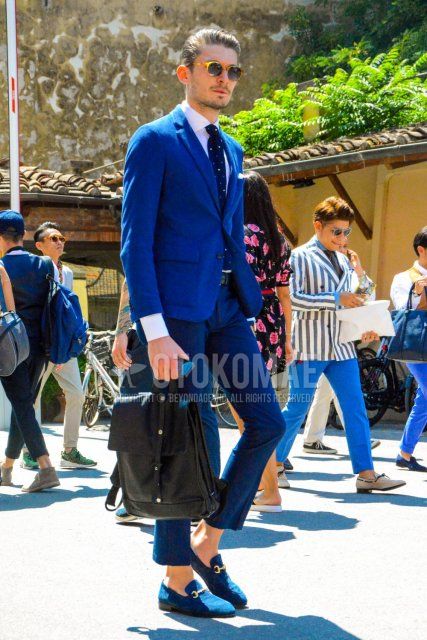Spring and fall men's coordinate and outfit with beige tortoiseshell sunglasses, plain white shirt, plain black leather belt, suede navy bit loafer leather shoes, plain black backpack, plain navy suit and plain navy knit tie.
