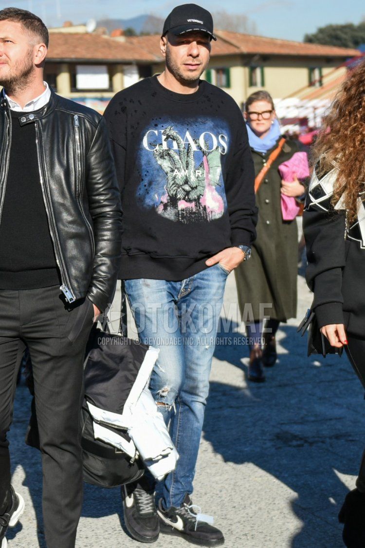 Men's fall/spring coordinate and outfit with black one-point baseball cap, plain black Amiri sweatshirt, plain blue damaged jeans, and Nike Off-White black low-cut sneakers.