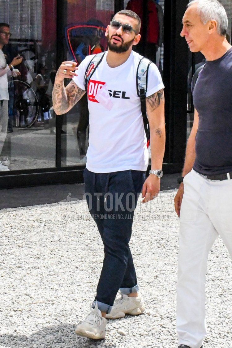 Summer men's coordinate and outfit with clear solid color sunglasses, Diesel white graphic t-shirt, dark gray solid color easy pants, and Adidas Easy Boost 500 white low-cut sneakers.