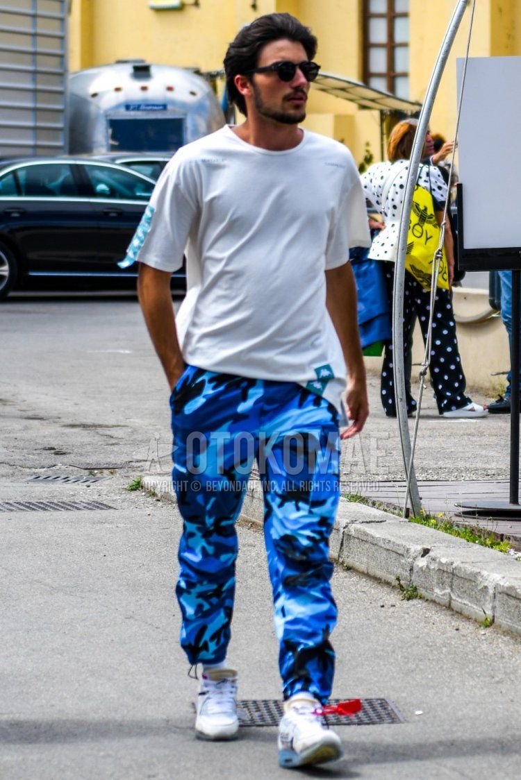 Men's summer coordinate and outfit with plain sunglasses, plain white t-shirt, blue camouflage cargo pants, plain white socks, and white low-cut sneakers.