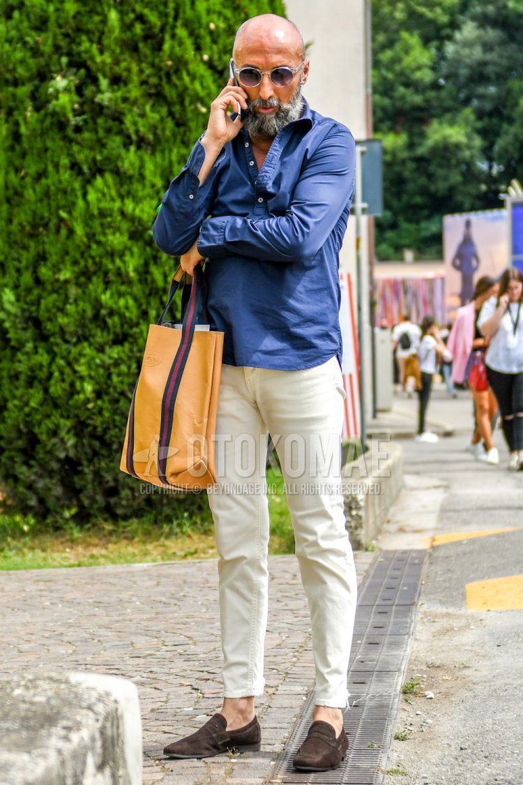 Men's spring/summer outfit with solid color sunglasses, solid color navy shirt, solid color white ankle pants, brown coin loafers leather shoes, suede shoes leather shoes, and solid color beige tote bag.