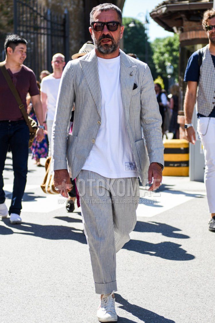 Men's spring/summer coordination and outfit with plain black sunglasses, plain white t-shirt, white low-cut sneakers, and gray striped suit.