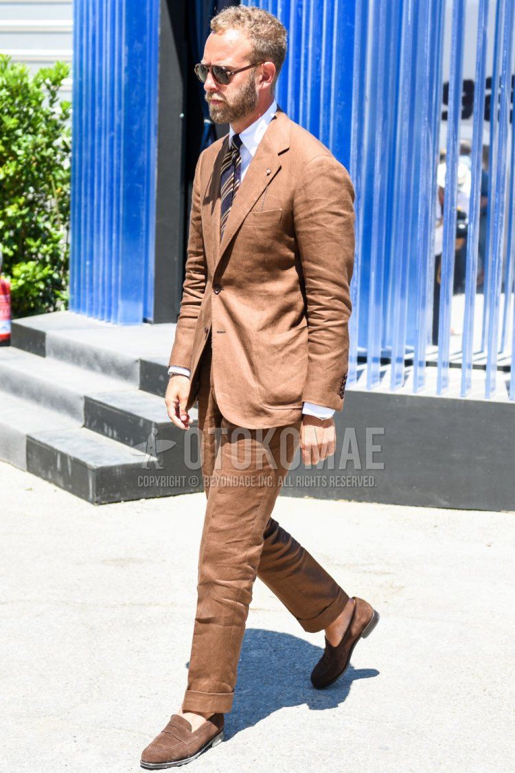 Men's spring and fall outfit with plain brown sunglasses, plain white shirt, suede brown coin loafer leather shoes, plain beige suit and navy regimental tie.