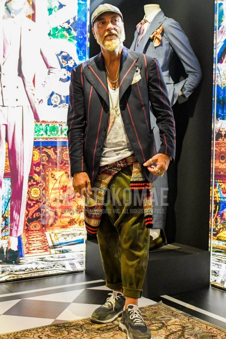 Men's spring/summer/fall outfit with gray cap, black/red striped tailored jacket, white top/inner t-shirt, olive green/green/beige camouflage sarouel pants, Balenciaga Triple S sneakers in gray low-cut.