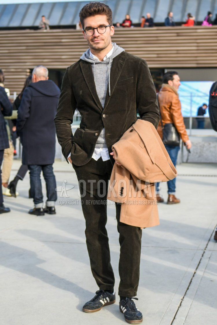 Men's spring and fall coordinate and outfit with brown tortoiseshell glasses, knit plain gray hoodie, plain white shirt, plain black socks, Adidas navy low-cut sneakers, and plain olive green suit.