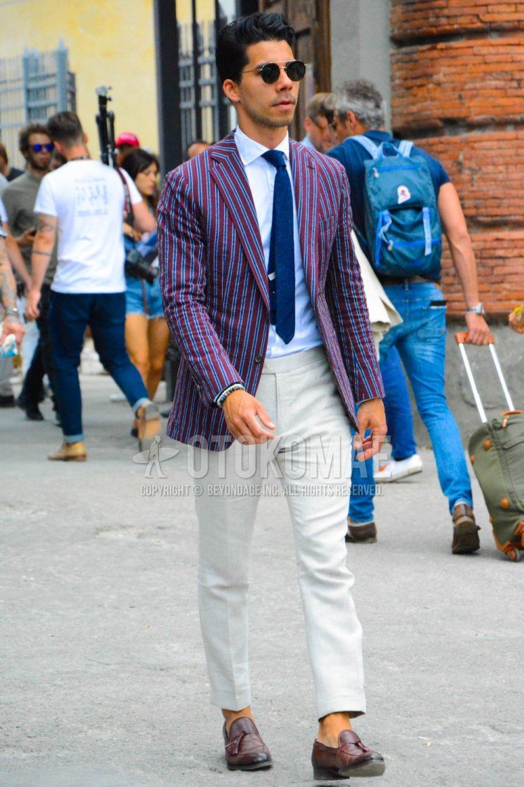 Men's spring and fall outfit with plain black sunglasses, purple striped tailored jacket, plain white shirt, plain beige slacks, plain beige beltless pants, brown tassel loafer leather shoes, and plain navy tie.
