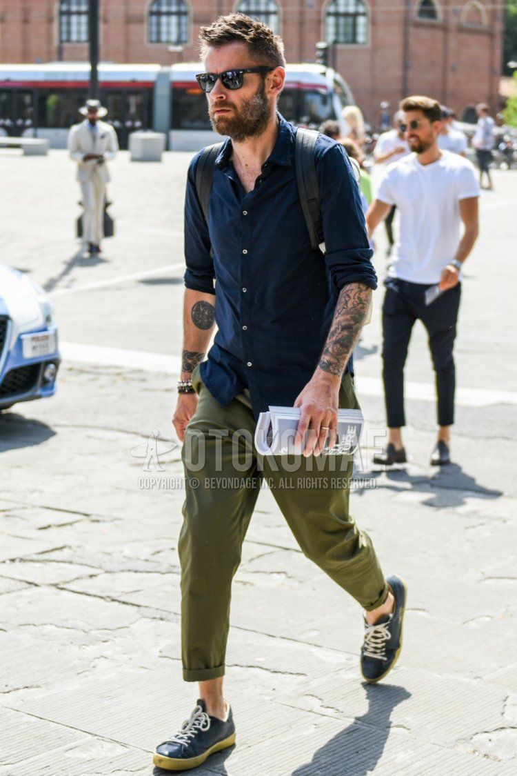 Spring and fall men's coordinate and outfit with plain black sunglasses, plain navy shirt, plain olive green cotton pants, and navy low-cut sneakers.