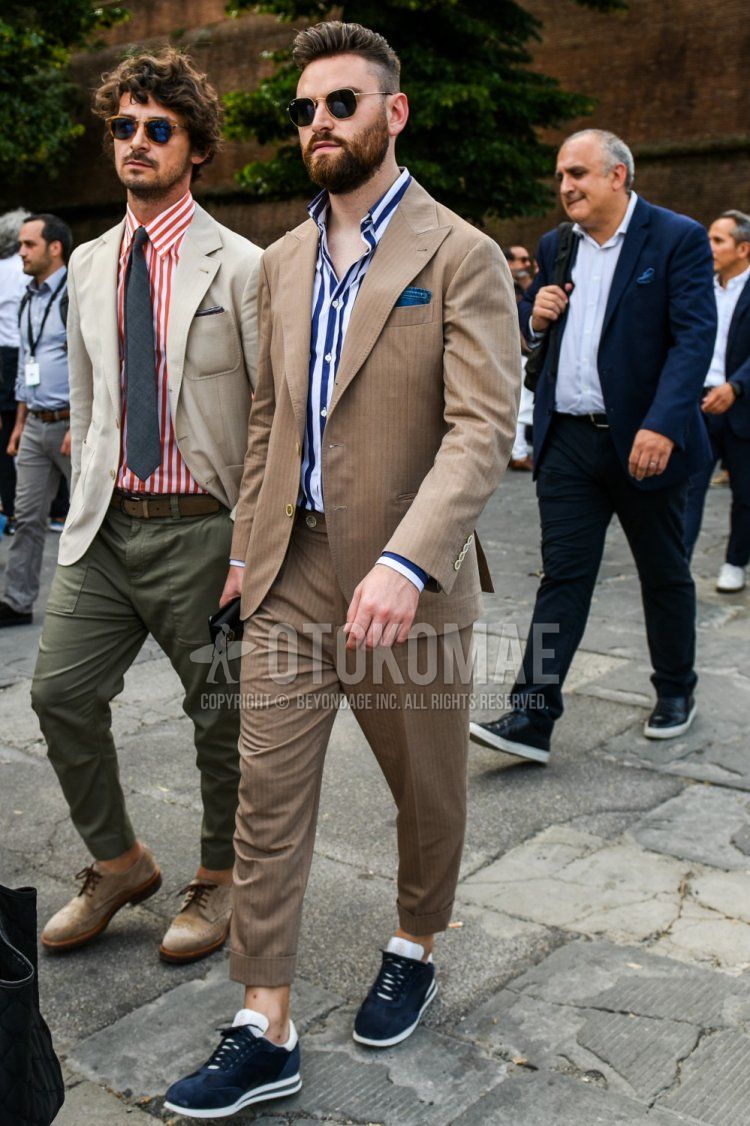 Men's spring and fall outfit and outfit with plain gold sunglasses, navy and white striped shirt, navy low-cut sneakers, and plain brown suit.