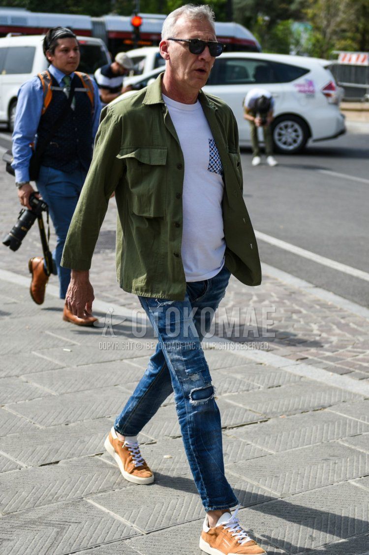 Men's spring and fall coordinate and outfit with Tom Ford plain black sunglasses, plain olive green shirt jacket, plain white t-shirt, plain blue damaged jeans, and brown low-cut sneakers.