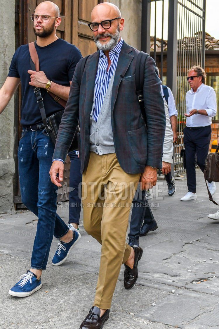Men's spring, summer, and fall coordination and outfit with plain glasses, multi-colored checked tailored jacket, plain gray cardigan, blue and white striped shirt, beige and brown bottoms cotton pants, and brown tassel loafer leather shoes.