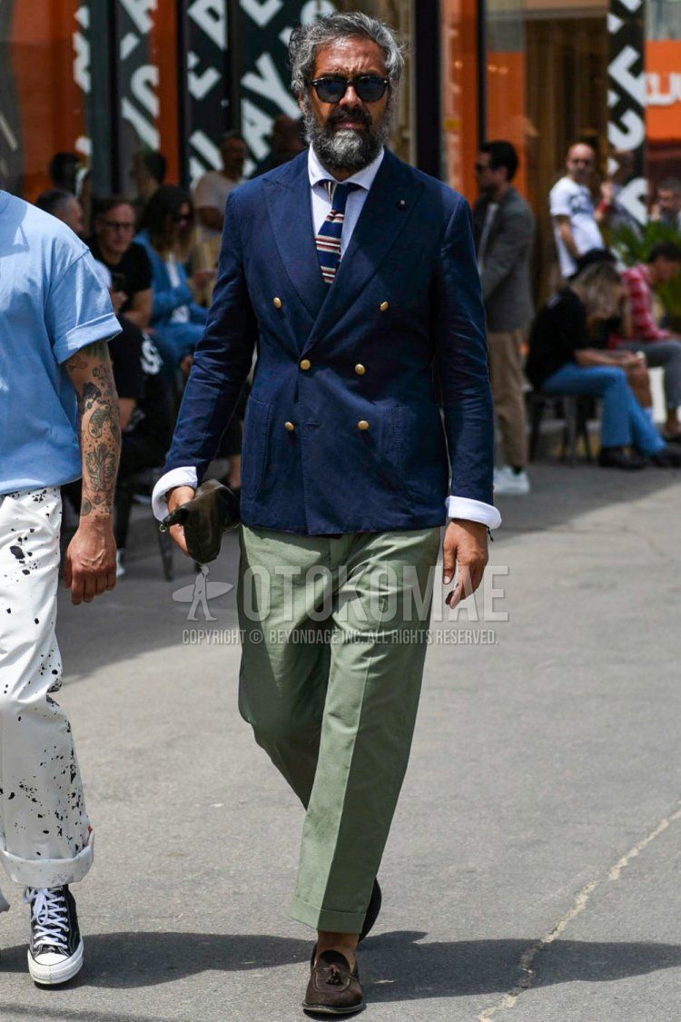 Men's spring/summer/fall outfit with plain black sunglasses, plain navy tailored jacket, plain white linen shirt, plain olive green slacks, suede brown tassel loafer leather shoes, and navy striped tie.