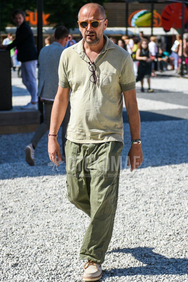 A summer men's coordinate and outfit with beige solid color sunglasses, green solid color polo shirt, and olive green solid color chinos.