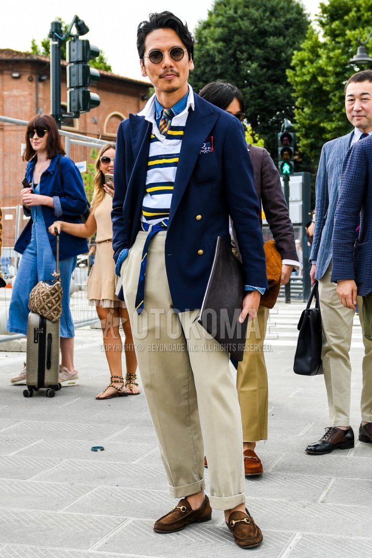 Solid black sunglasses, solid navy tailored jacket, solid blue denim/chambray shirt, polo shirt with yellow and white stripes, navy striped tape belt with tie, solid beige chinos, suede Gucci brown bit loafer leather shoes, solid black clutch bag/second bag/drawstring, multi-colored checked tie, blue regimental tie, spring/fall men's coordinate and outfit.