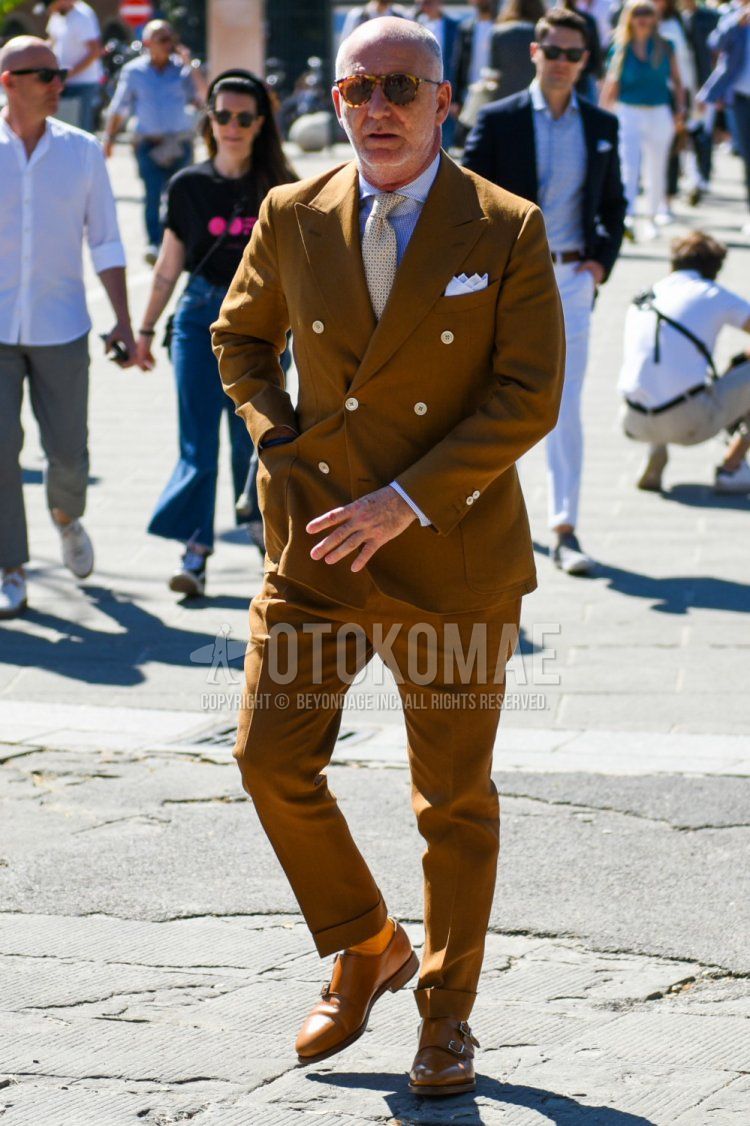 Men's spring/autumn coordination and outfit with brown tortoiseshell sunglasses, white top/inner shirt, solid orange socks, brown monk shoes leather shoes, solid beige suit, beige necktie tie.